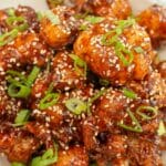 A plate of crispy Korean Fried Cauliflower with scallions and sesame seeds.