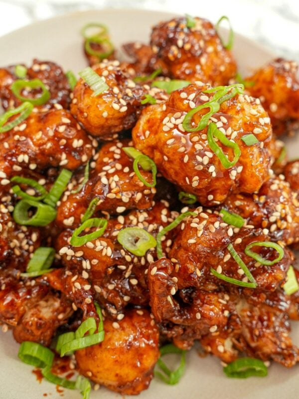 A plate of crispy Korean Fried Cauliflower with scallions and sesame seeds.