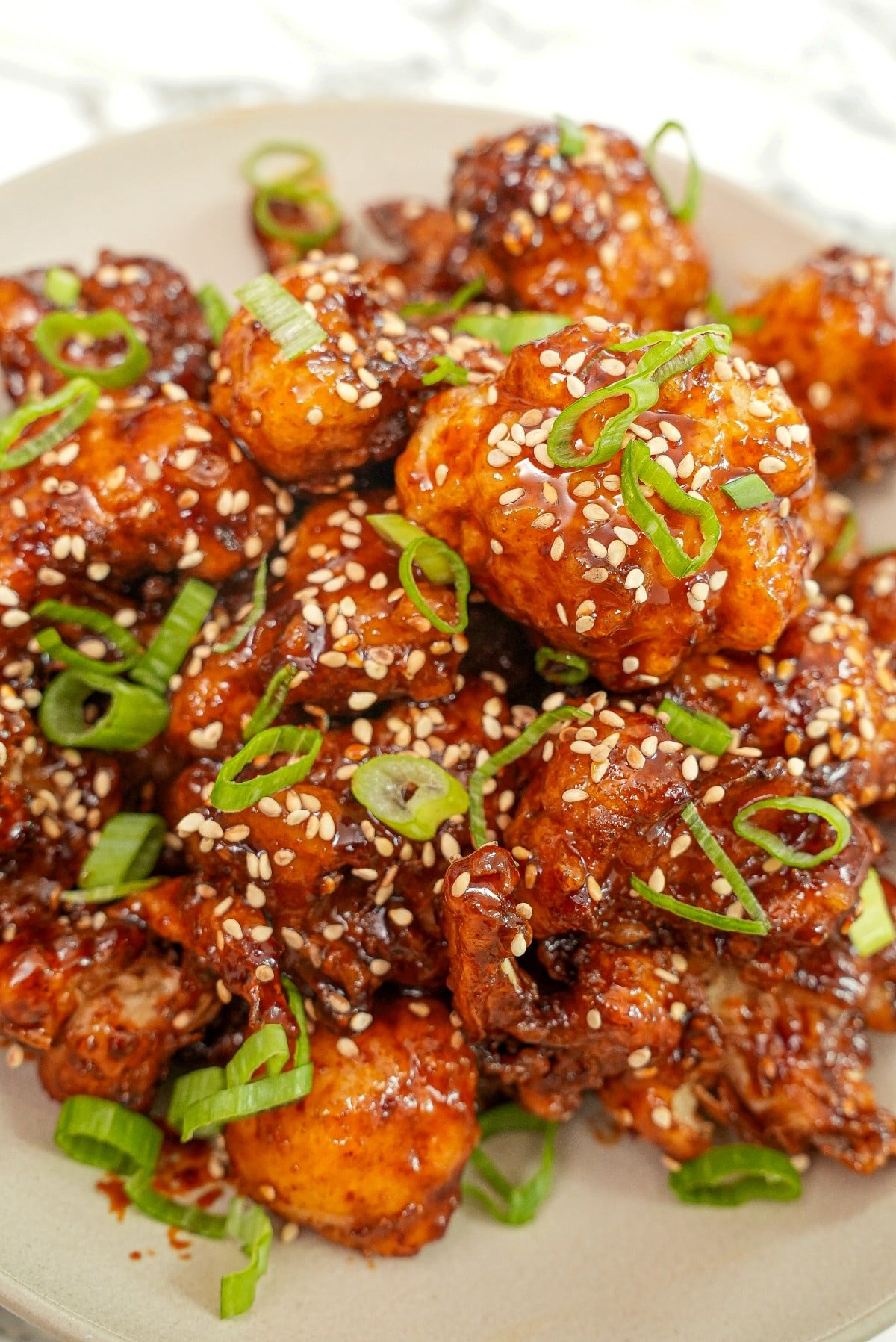 A plate of crispy Korean Fried Cauliflower with scallions and sesame seeds.