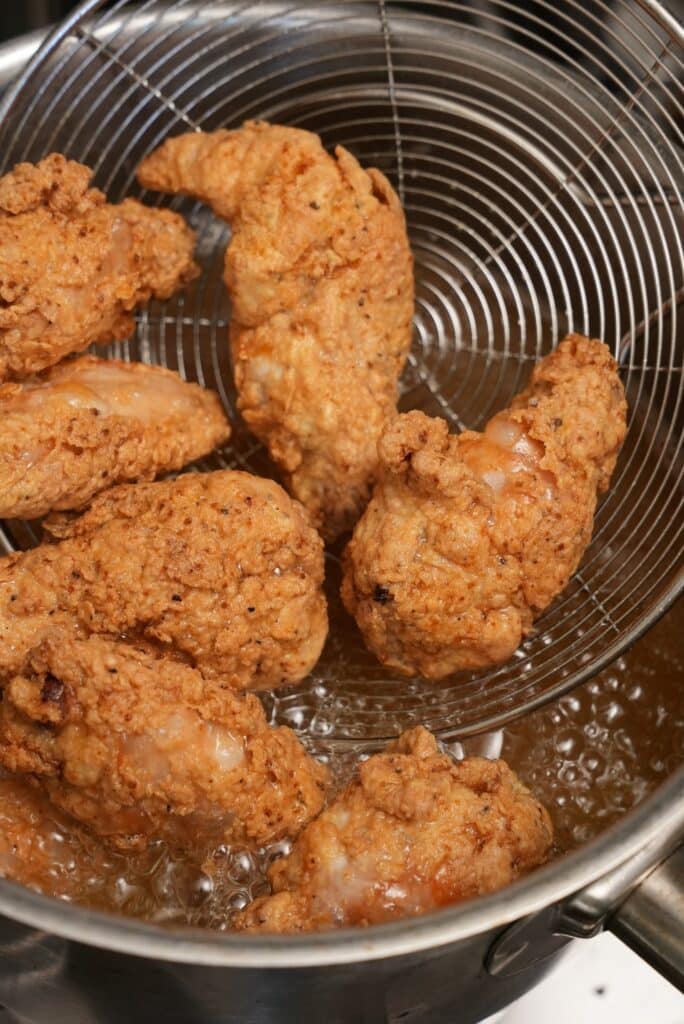 Chicken wings fried in oil in a strainer