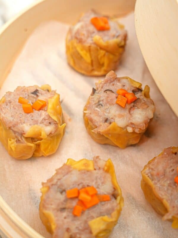 Steamed siu mai dumplings in a bamboo steamer.