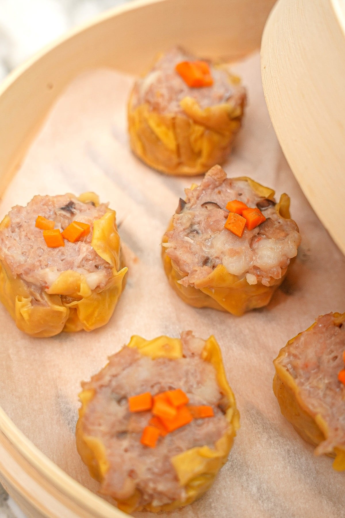 Steamed siu mai dumplings in a bamboo steamer.