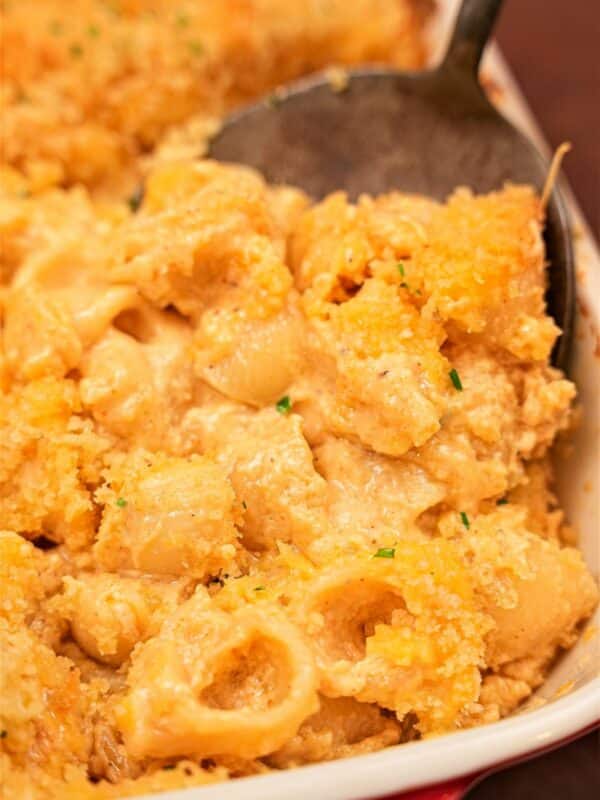 Baked Mac and Cheese in a pan being scooped with a spatula.