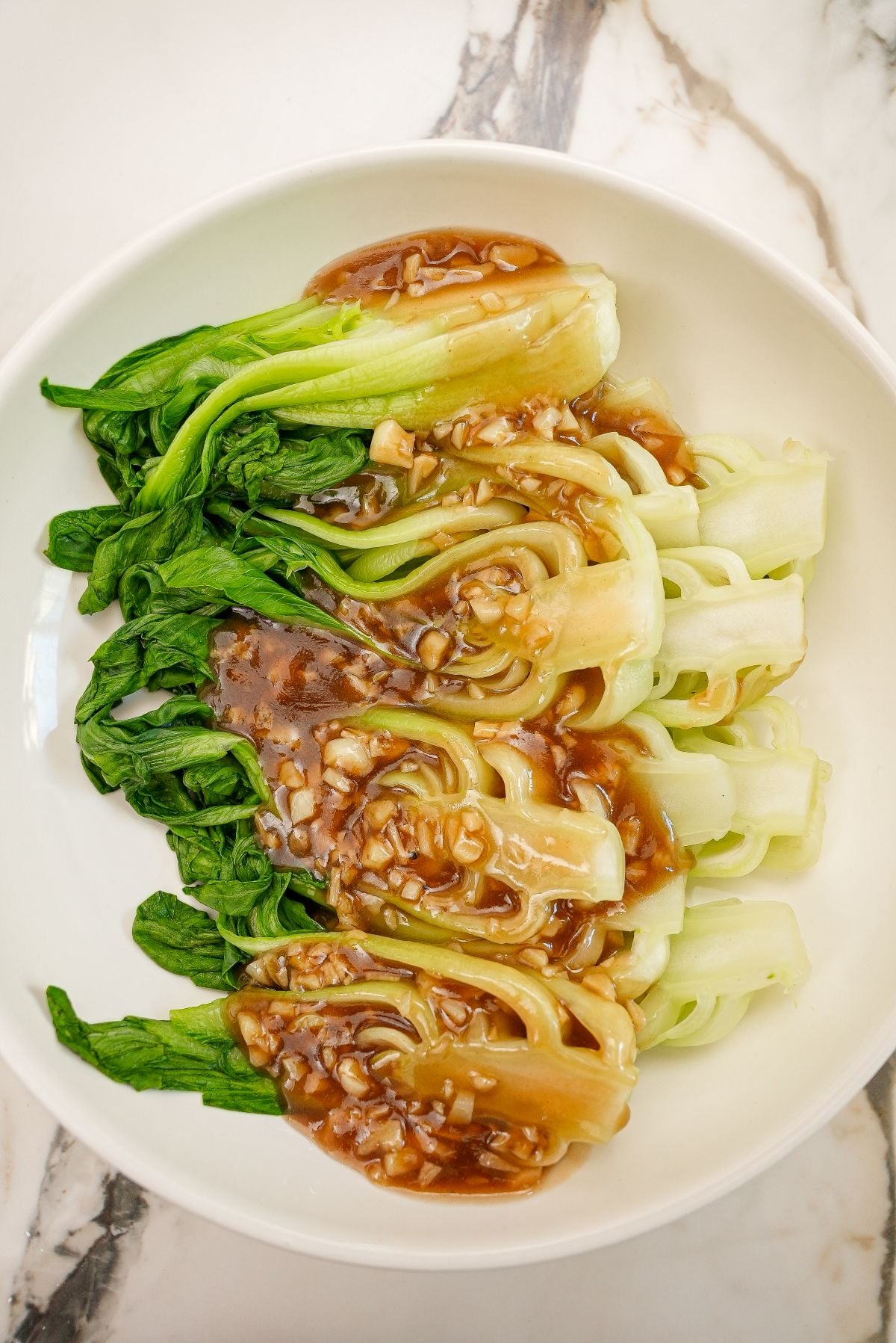 A bowl of bok choy with garlic sauce.