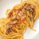 A bowl with an authentic carbonara topped with crispy guanciale.