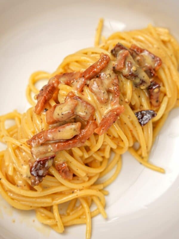 A bowl with an authentic carbonara topped with crispy guanciale.
