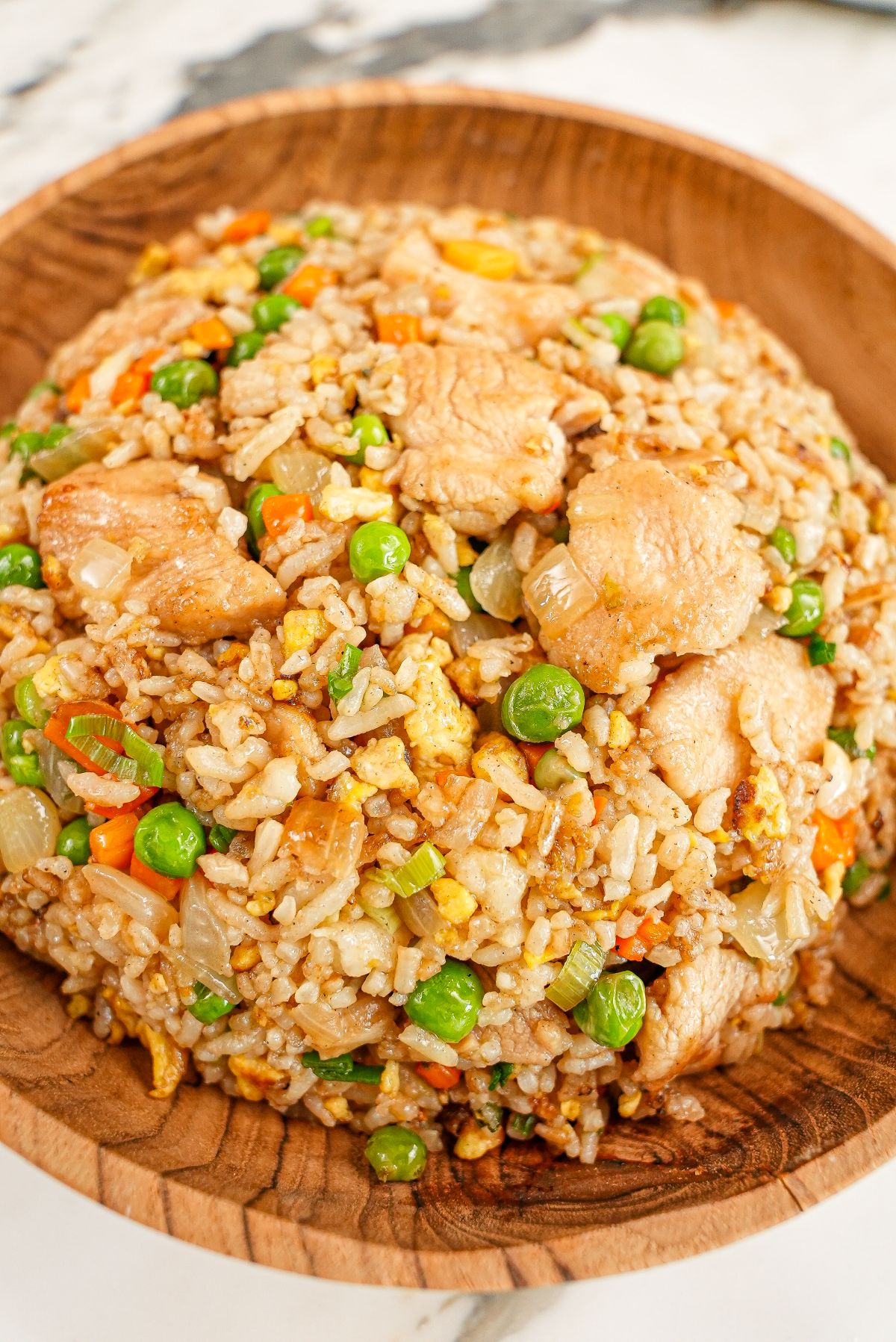 Chicken fried rice in a wooden bowl.