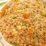 Egg Fried Rice on a plate with eggs, carrots, pea, rice, and seasonings.