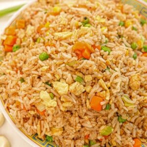 Egg Fried Rice on a plate with eggs, carrots, pea, rice, and seasonings.