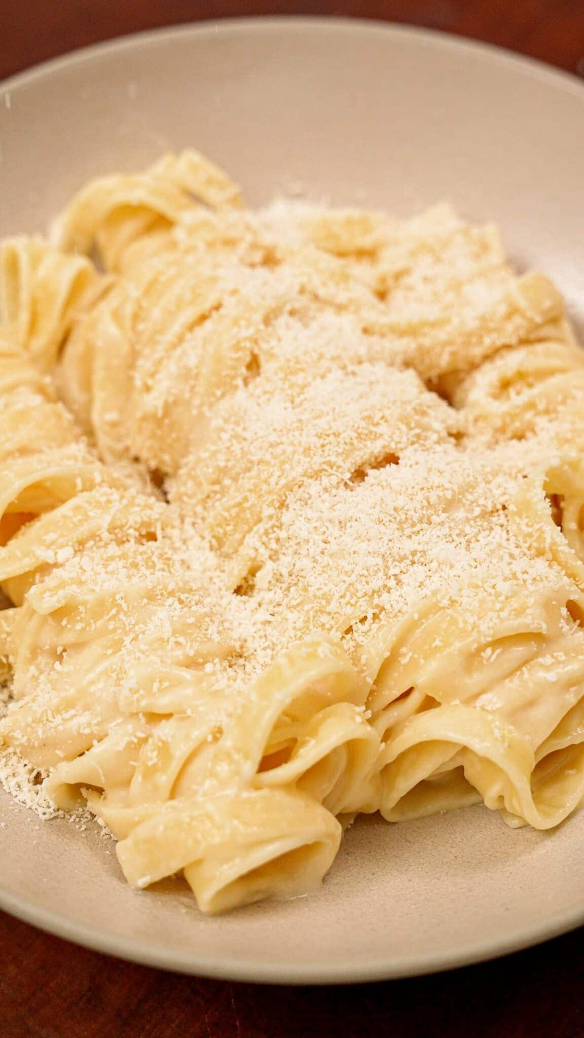 A bowl of plated Fettuccine Alfredo made with fettuccine pasta, butter, parmesan cheese, and pasta water.