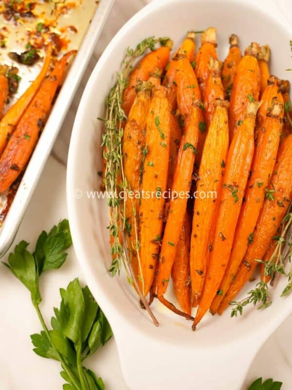 A bowl of honey roasted carrots with fresh herbs.