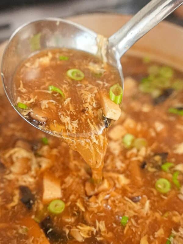 A ladle with easy and authentic hot and sour soup cooked in a pot.