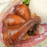 Soy sauce chicken drumsticks on a plate with white rice.