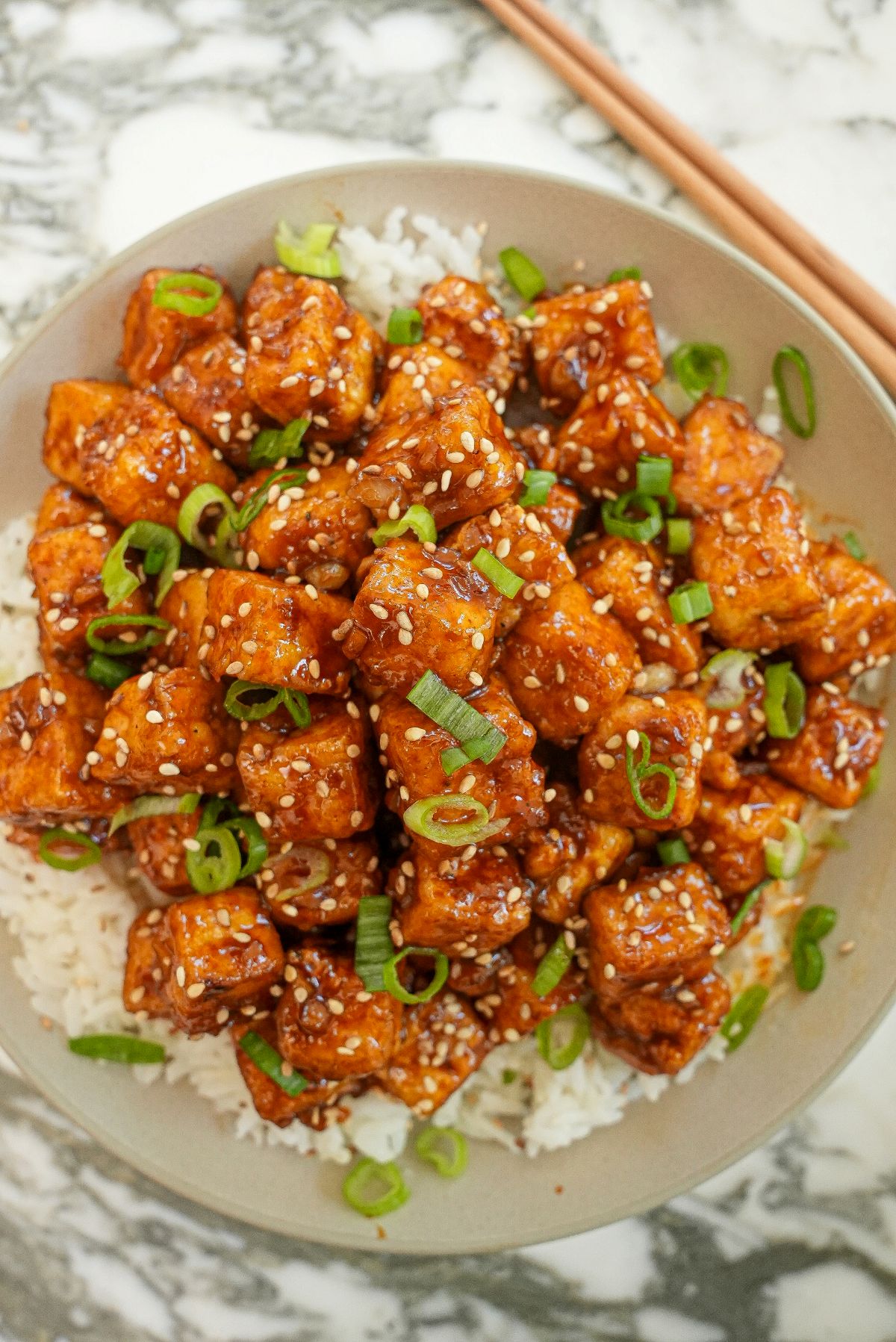 Spicy Honey Garlic Tofu on  bowl of rice with green onions.