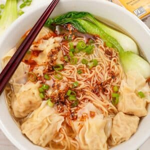 Wonton Noodle Soup in a bowl with bok choy, wontons, wonton noodles, scallions and chili oil.