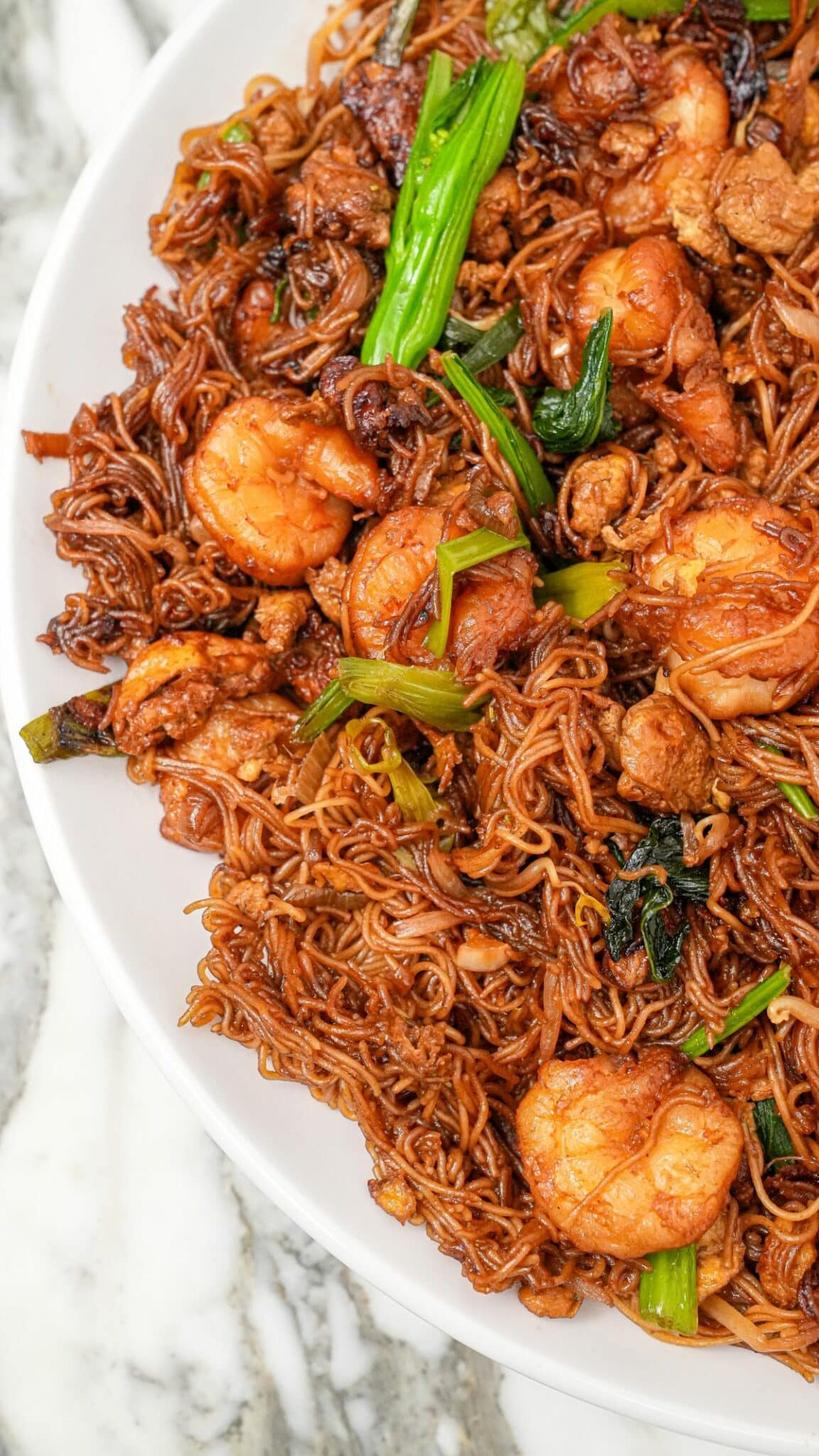 Bihun Goreng (Beehoon Goreng) on a plate with shrimp, vegetables, and noodles.
