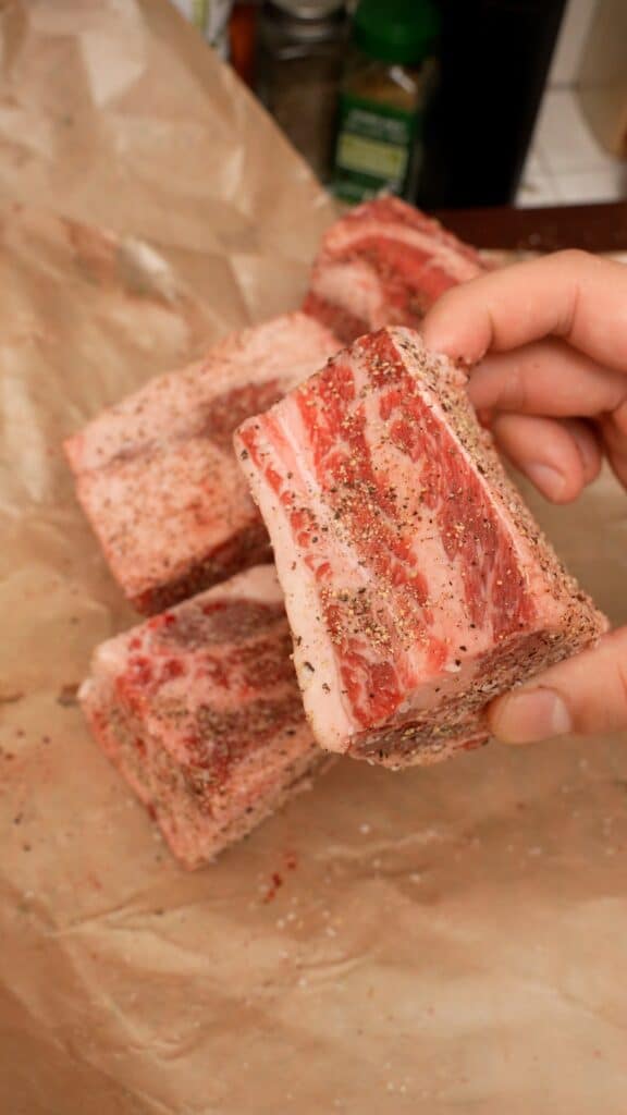 Beef short ribs seasoned with kosher salt and black pepper on all sides.