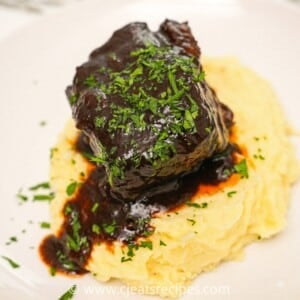 Braised beef short ribs on a plate with mashed potatoes.