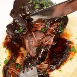 Braised short ribs on a plate of mashed potatoes.