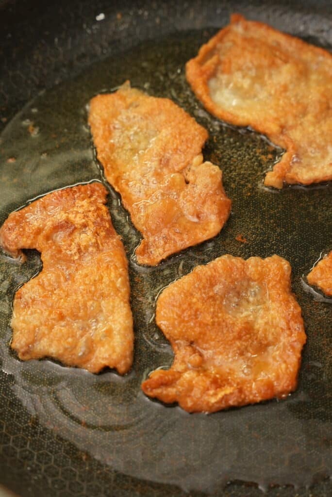 Chicken skin chips being fried in rendered chicken fat.