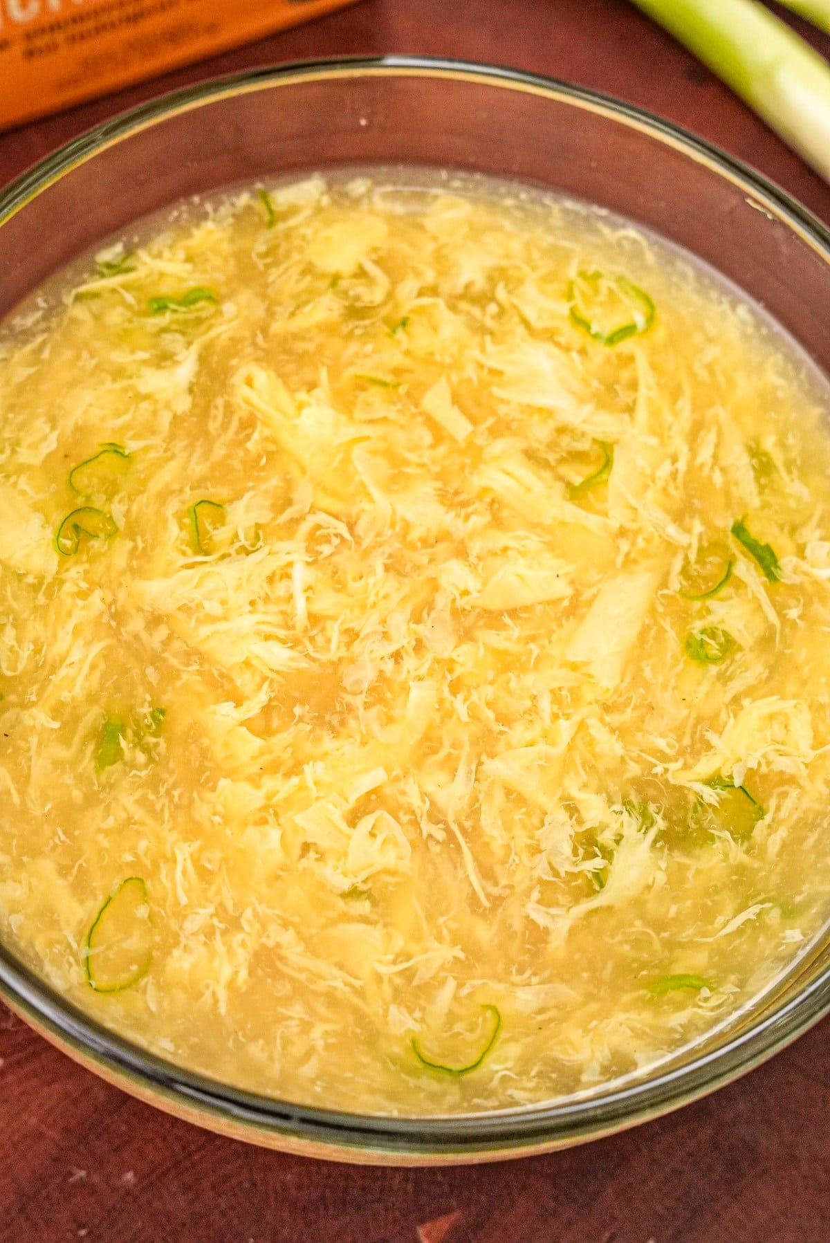 Egg drop soup in a glass bowl with scallions.