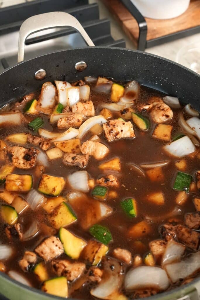 Water added to the sauce to simmer and cook the pork belly and vegetables with black bean paste.