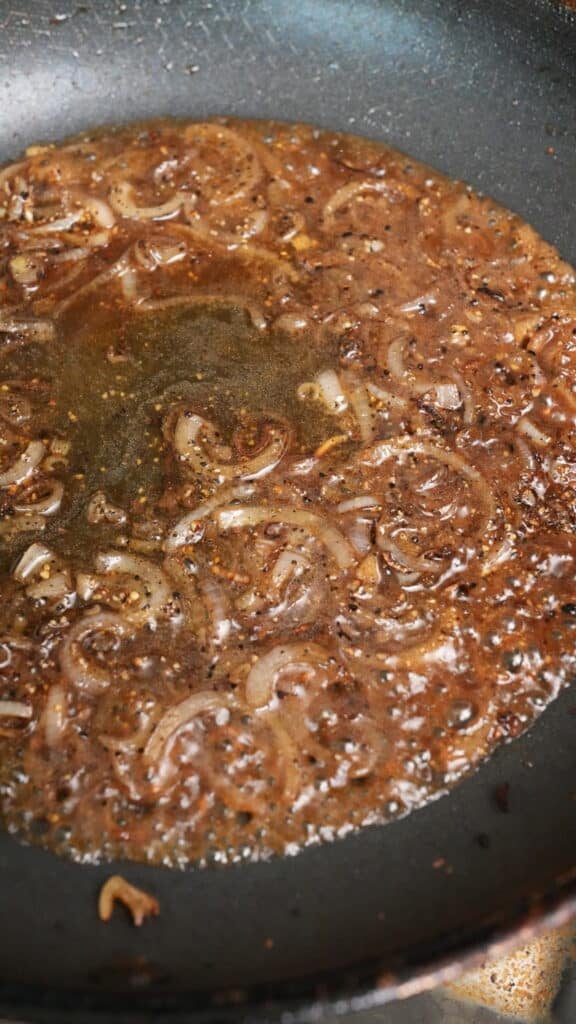 Cognac or Brandy cooking in a pan with shallots and black pepper.