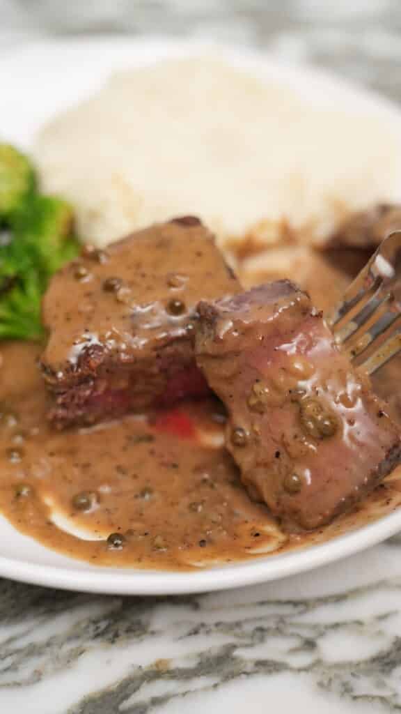A piece of steak covered with peppercorn sauce.