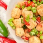 Salt and pepper tofu in a bowl with peppers and seasonings.