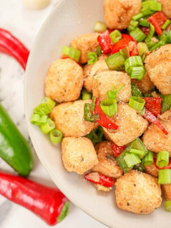 Salt and pepper tofu in a bowl with peppers and seasonings.