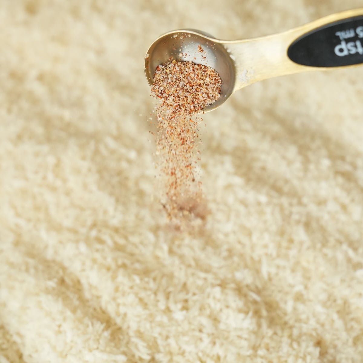 The seasoning mix being added to a tray of panko breadcrumbs.