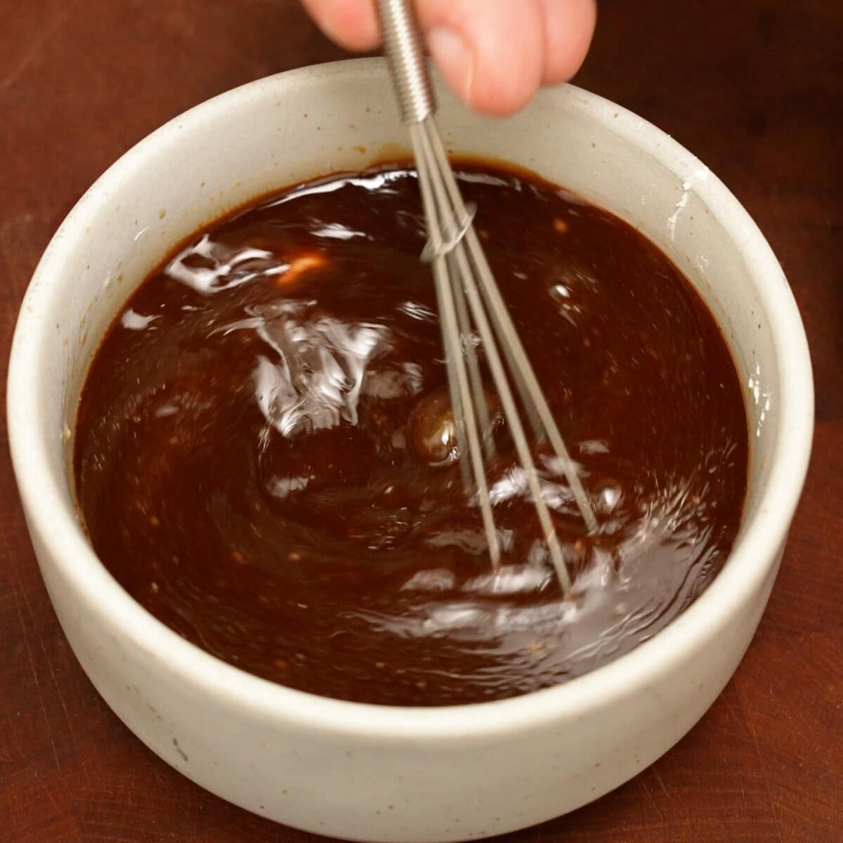 Bourbon Chicken sauce being mixed in a small bowl with a whisk.