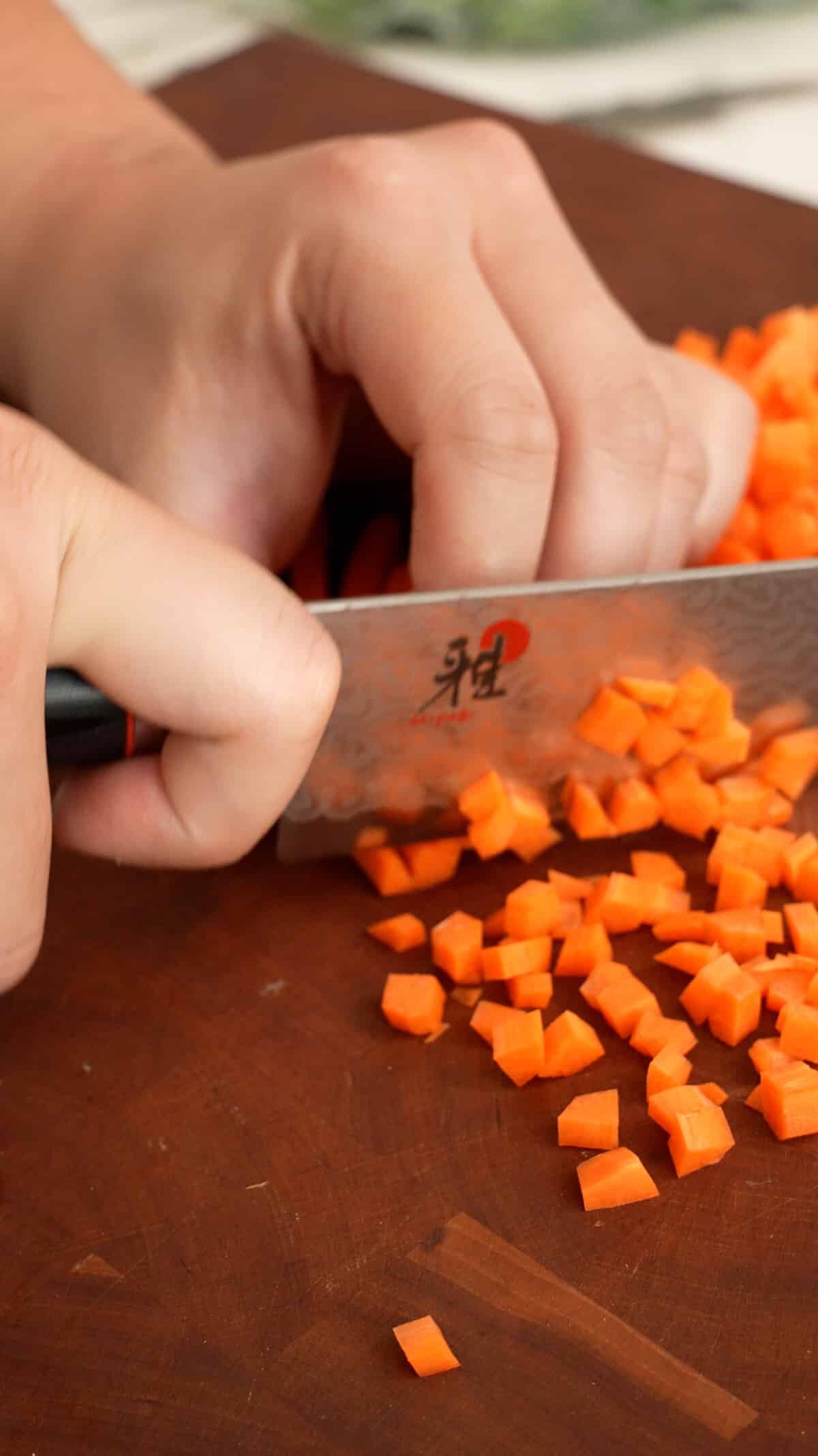 Cutting carrots on a cutting board with a knife.