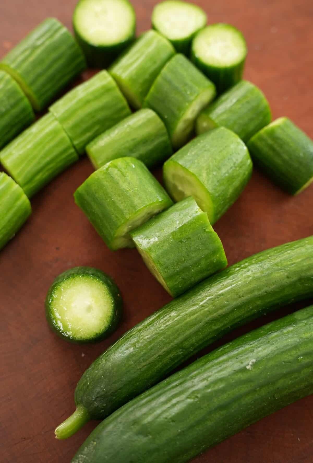 Whole cucumbers and cucumber rounds on a cutting board.