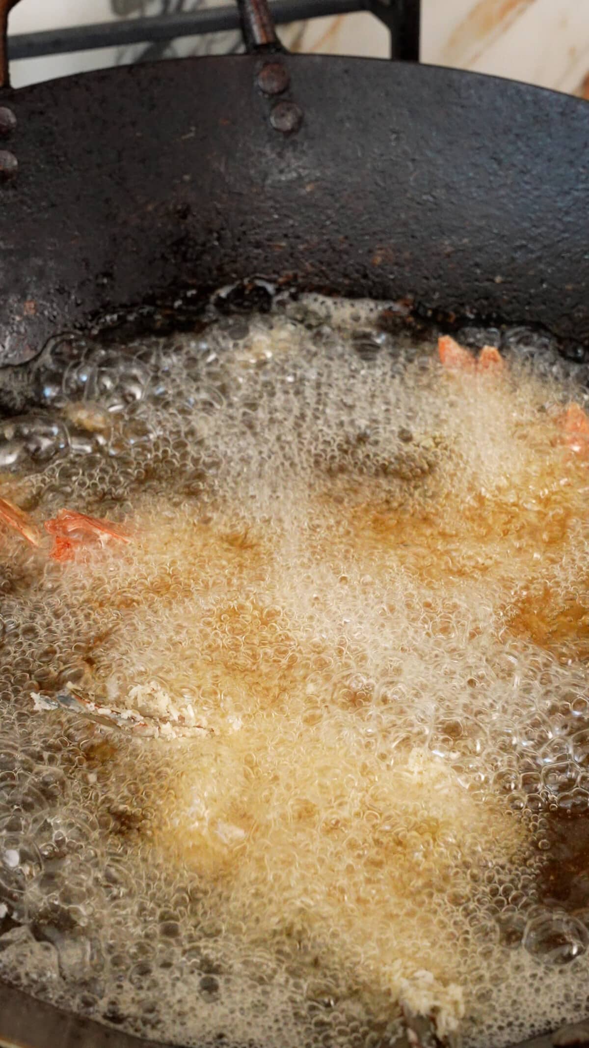 Coconut Shrimp frying in oil in a wok.