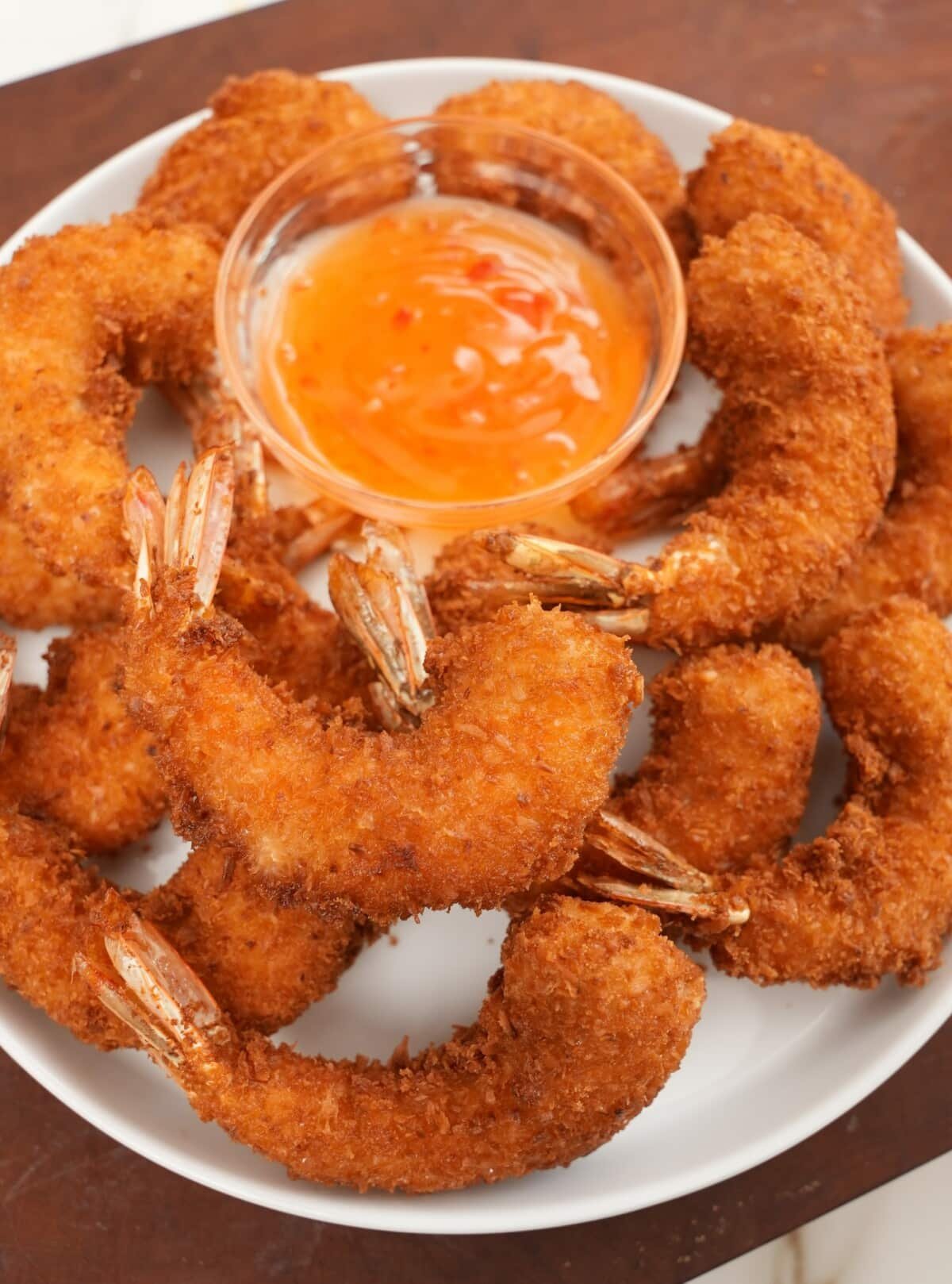 Fried coconut shrimp with sweet chili sauce on a plate.