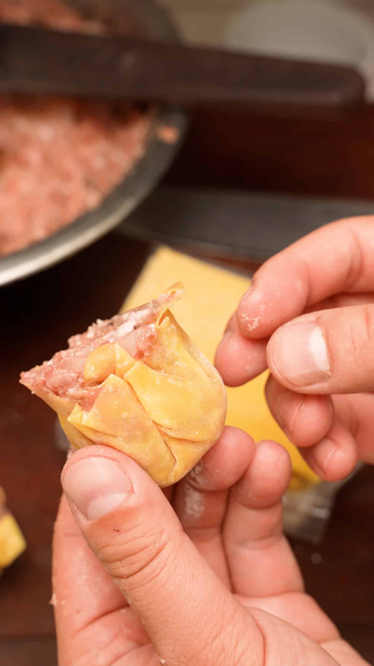 A finished Siu Mai dumpling being held in a hand.