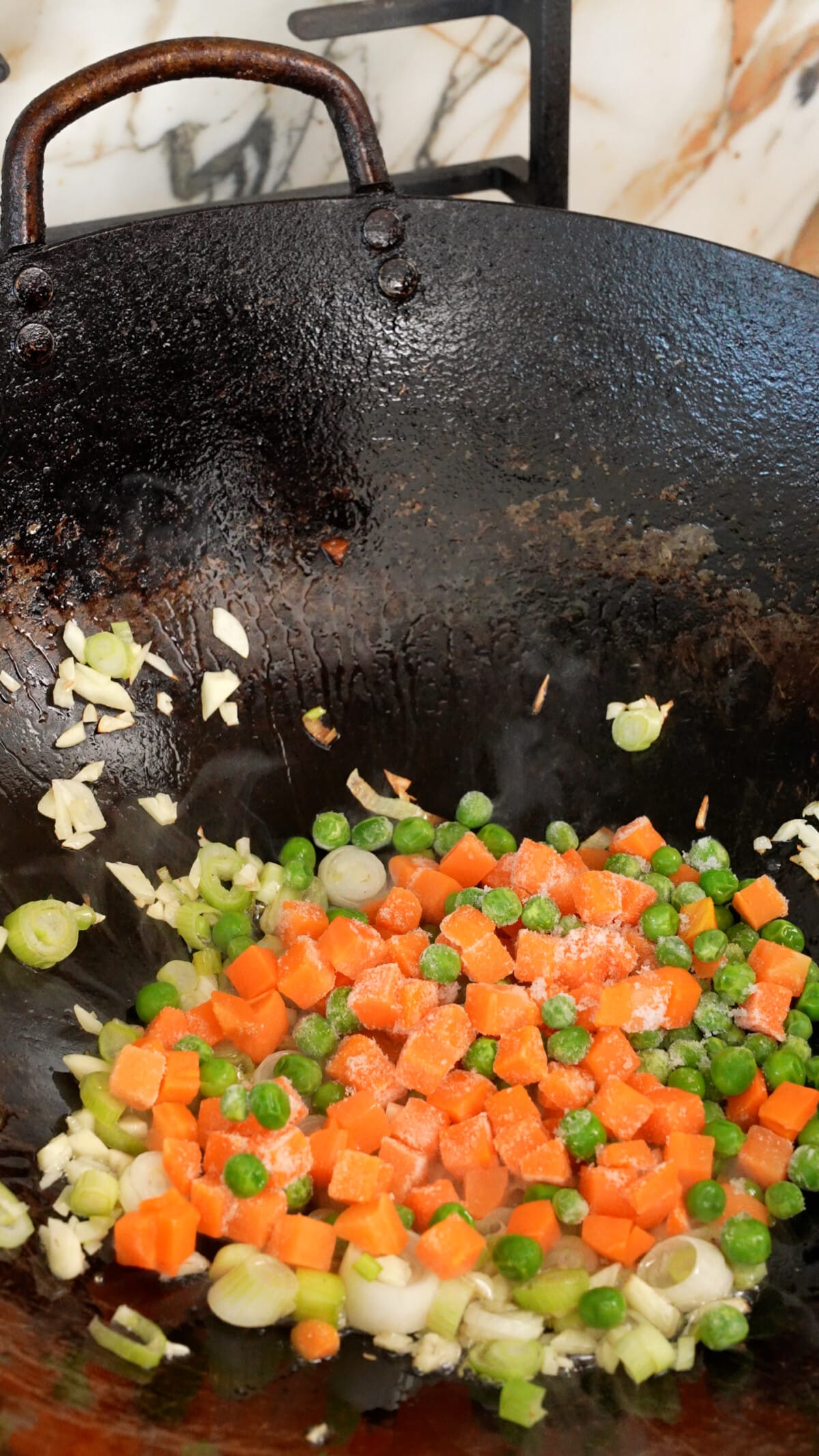 Sauteing aromatics and vegetables in a wok.