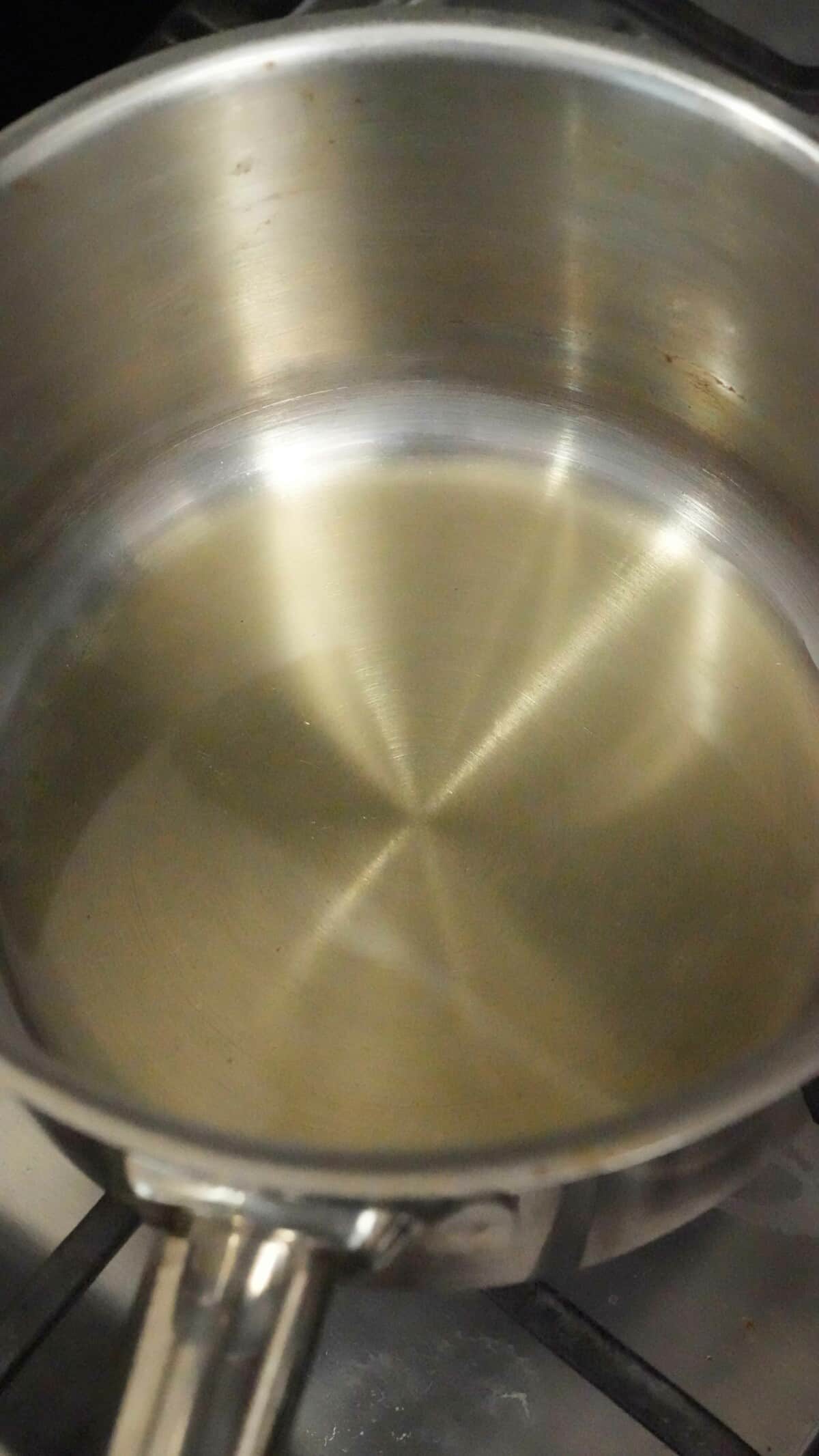 Two tablespoons of avocado oil being heated up in a small saucepan.
