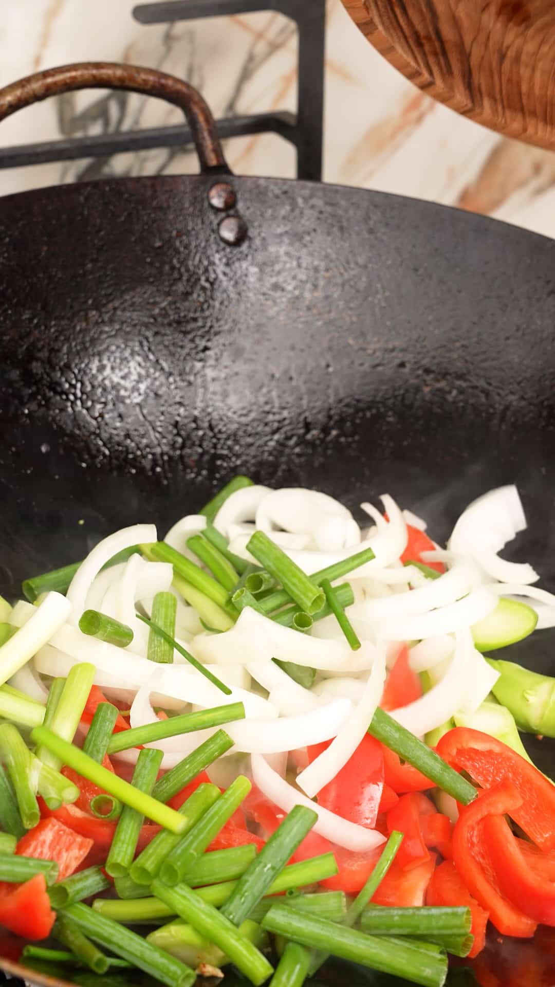Onions and peppers being cooked in a wok.