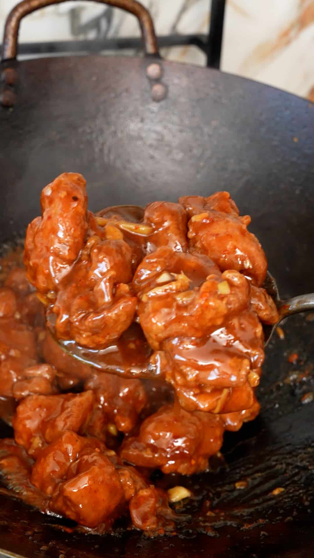 General Tso's Chicken coated in sauce in a wok.