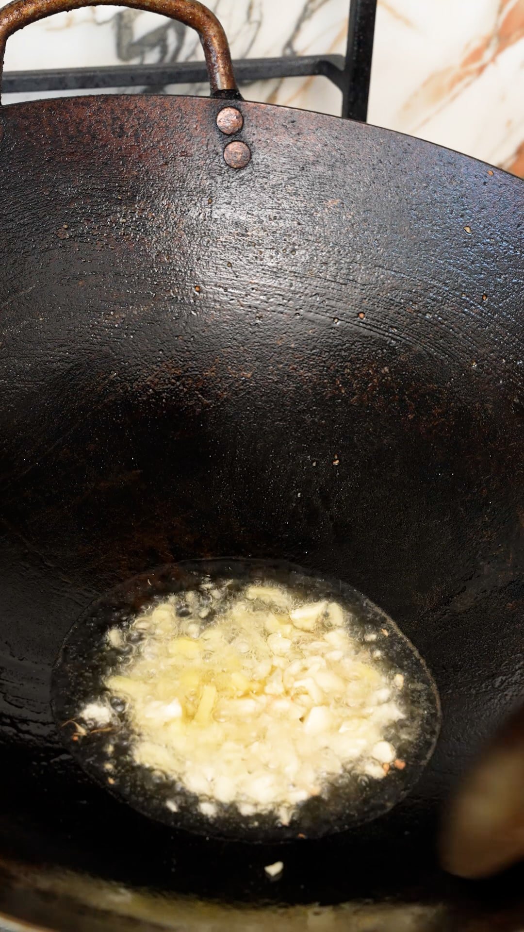 Garlic and ginger sauteing in oil in a wok.