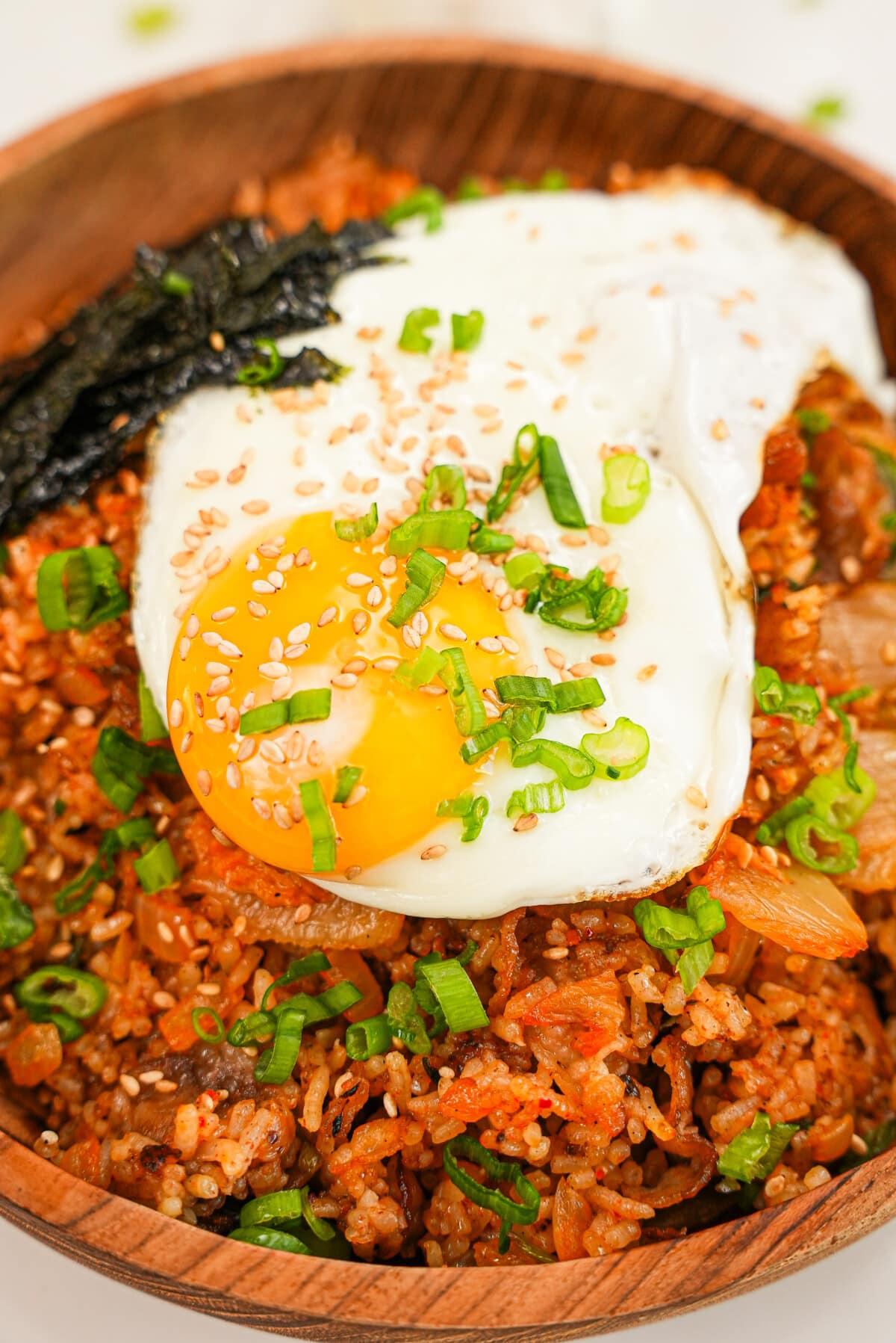 Kimchi Fried Rice on a bowl topped with scallions and a fried egg.