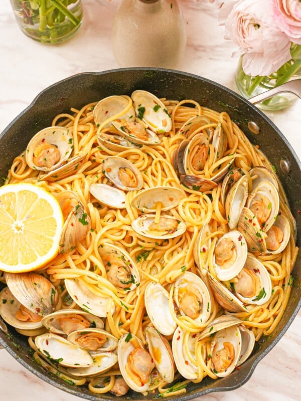 Linguine with clams in a pan topped with lemon and fresh parsley.