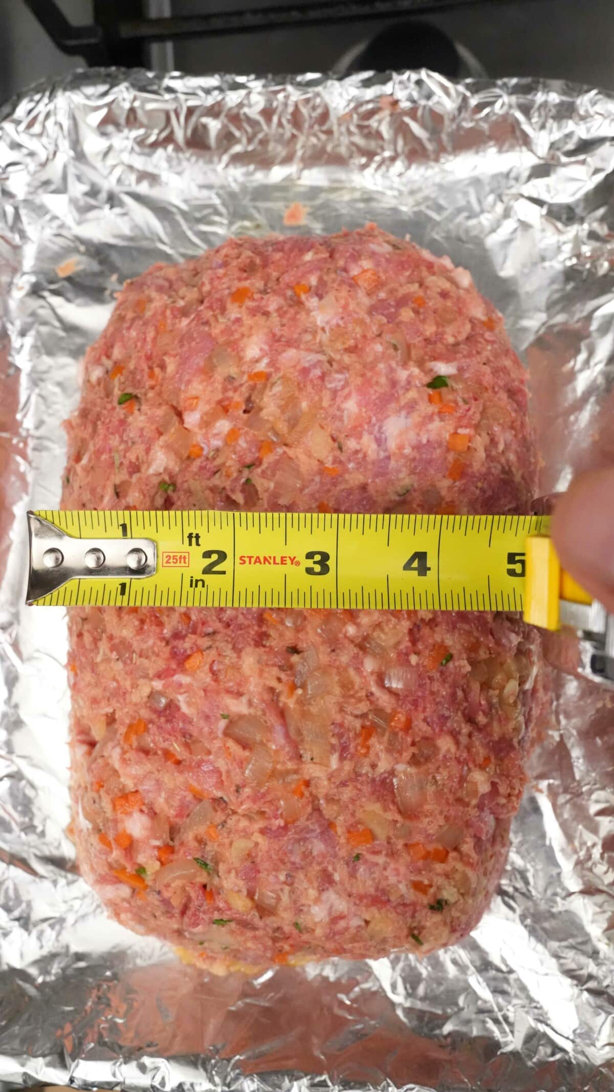 A measuring tape showing the width of the meatloaf.