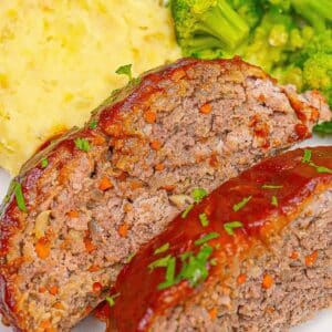A plate of meatloaf slices with mashed potatoes and broccoli.