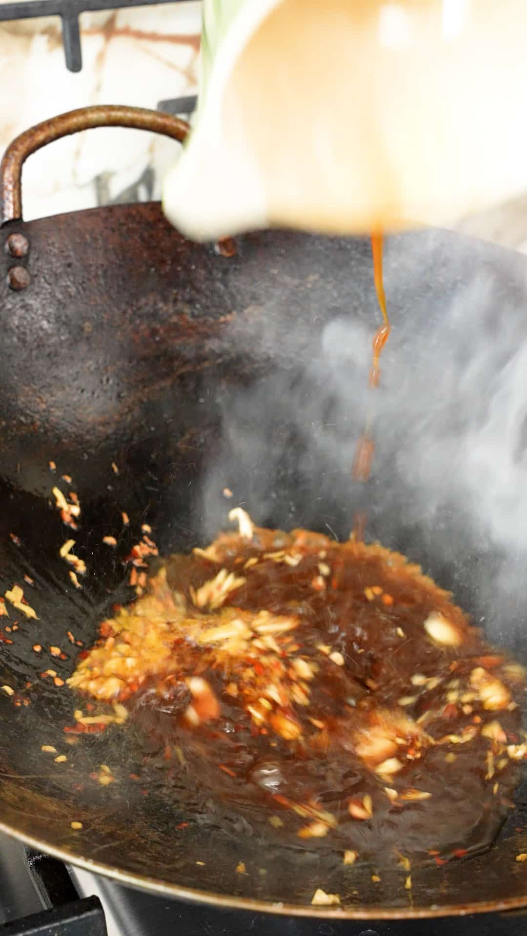 Orange sauce being added to a wok.