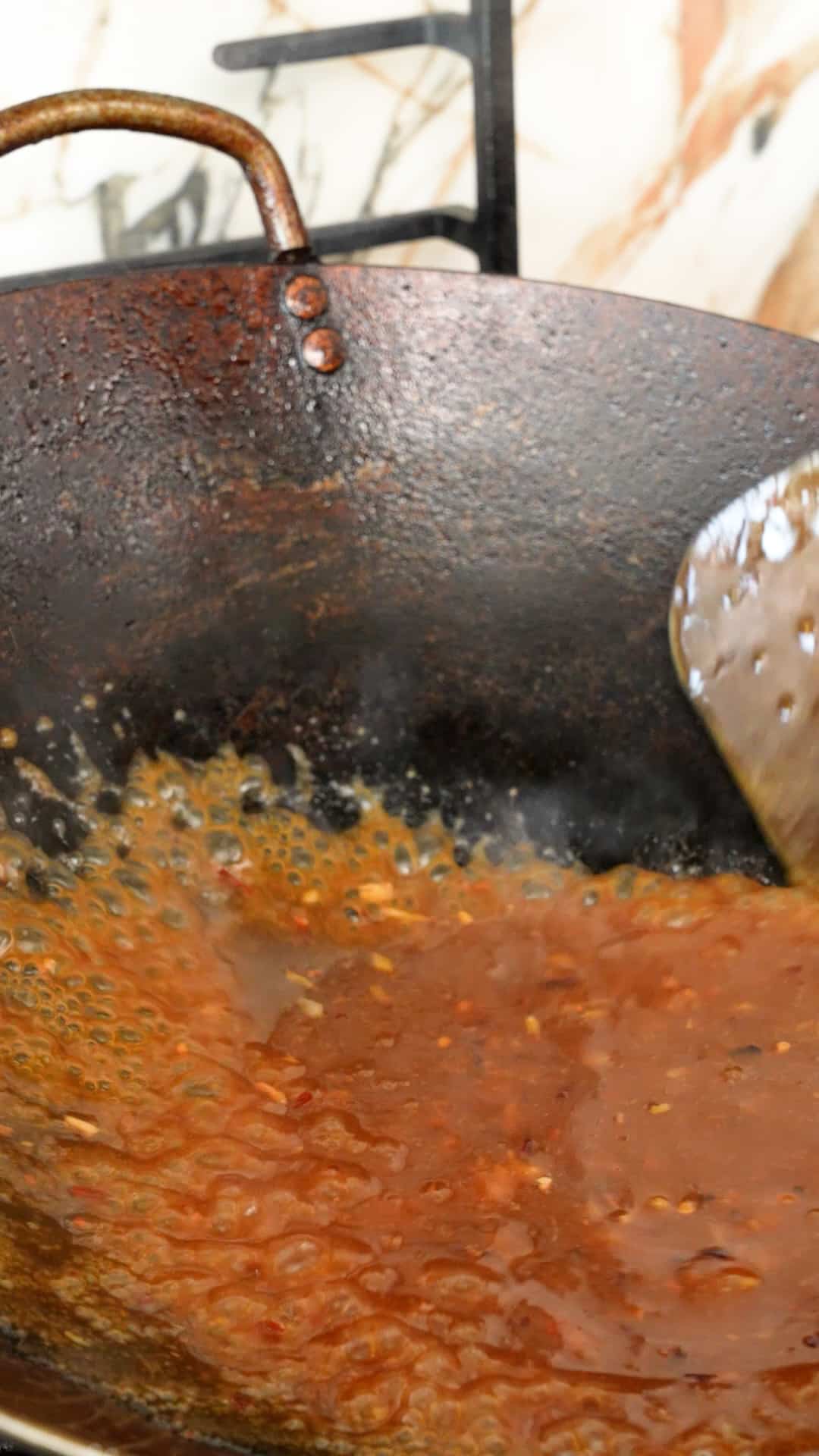Thickening orange sauce in a wok for orange chicken.