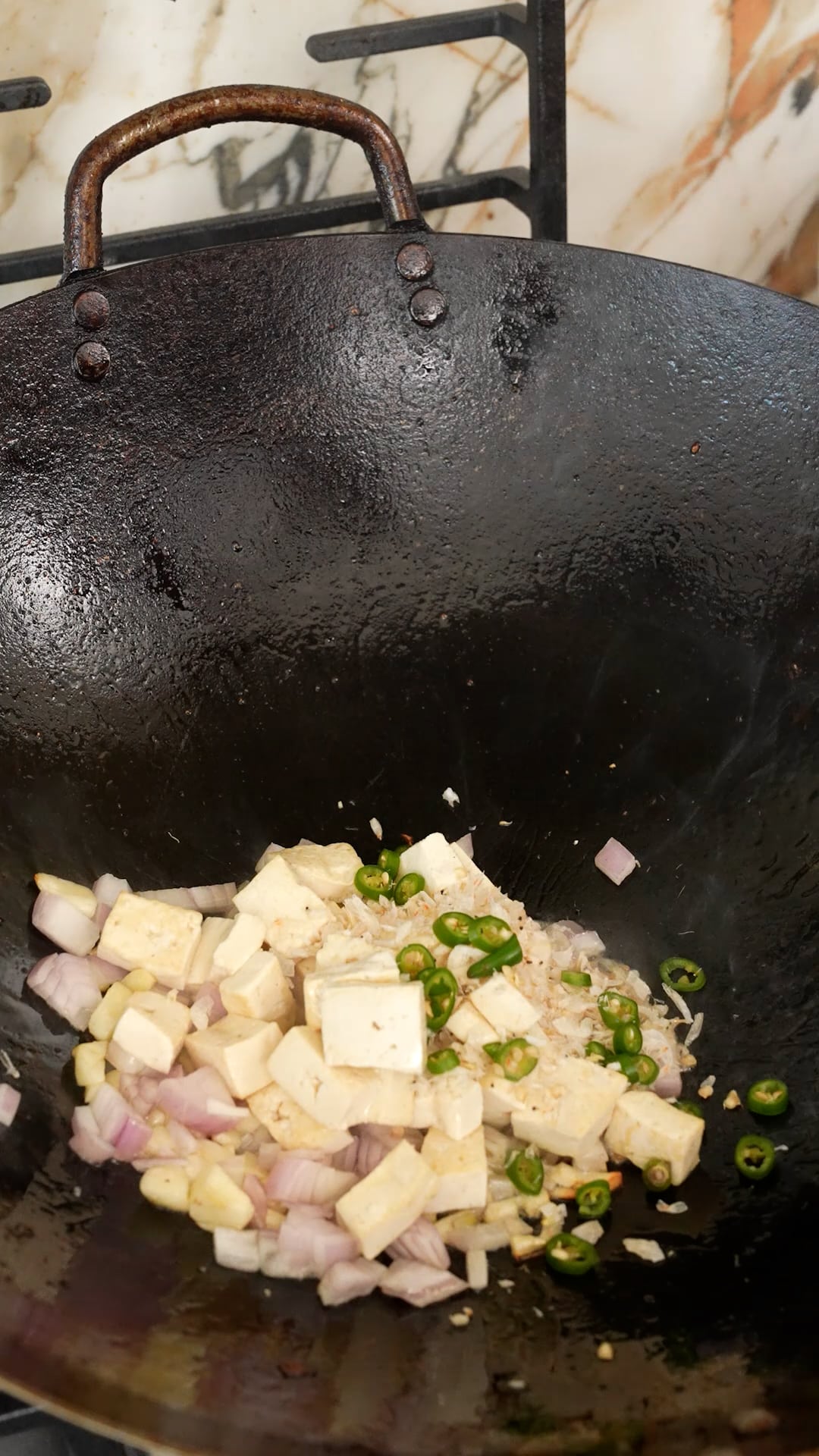 Cooking garlic, shallots, tofu, and Thai chili peppers in a wok.