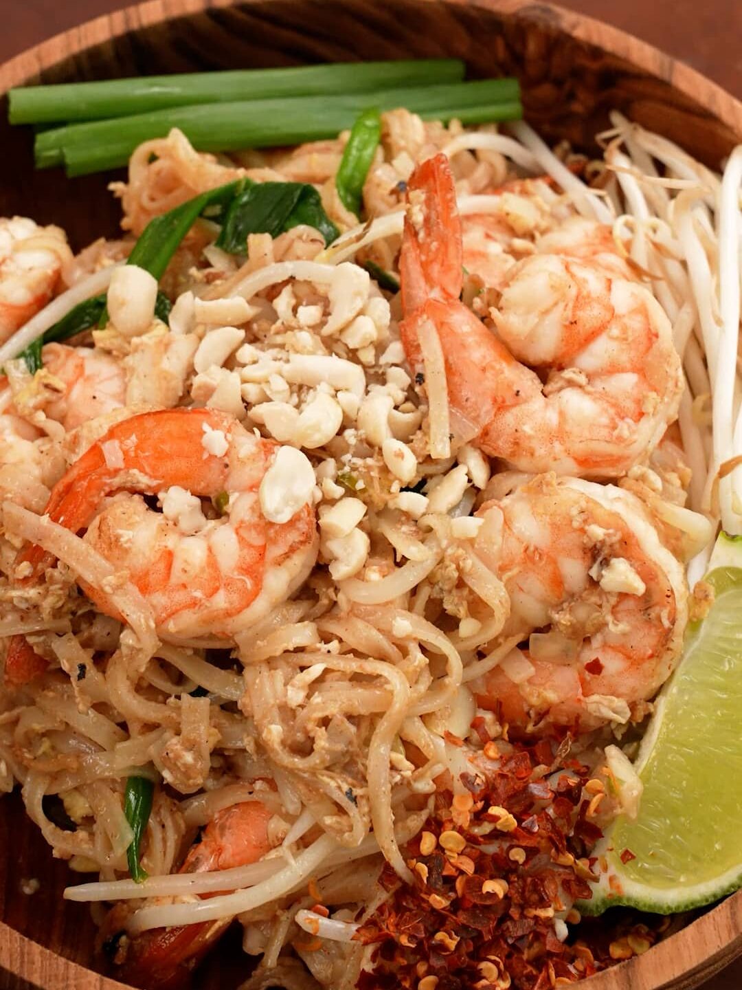 Pad Thai plated in a wooden bowl.